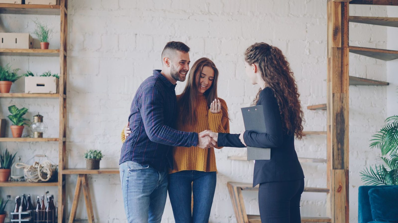 A real-estate agent shaking hands with a happy couple after closing
